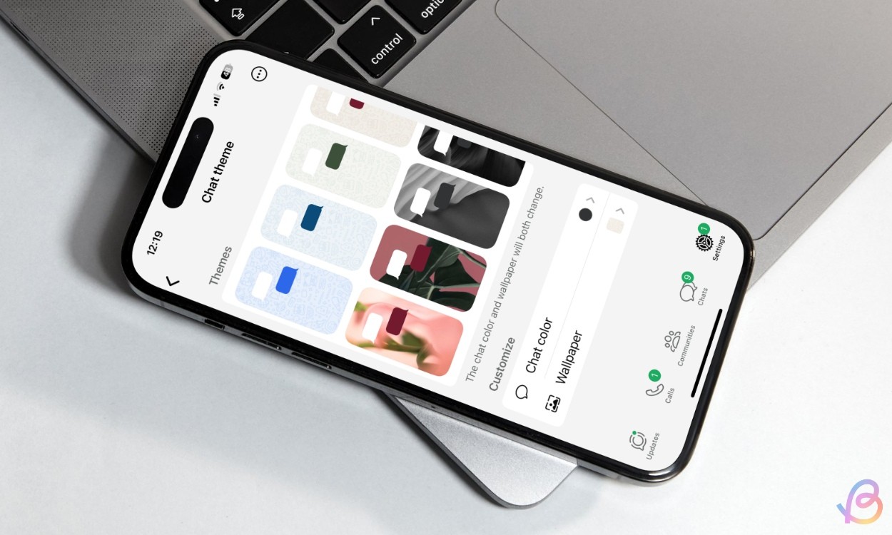 Ảnh chụp iPhone đặt trên MacBook hiển thị màn hình chủ đề chat bên trong ứng dụng WhatsApp trên iOS